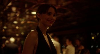 Movie still from “Side Effects” (2013), directed by Steven Soderbergh – A woman in a black dress smiling for the camera; Close Up shot, Over the shoulder angle