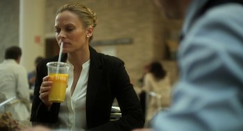 Movie still from “Side Effects” (2013), directed by Steven Soderbergh – A woman sitting at a table with a drink in her hand; Medium shot, Over the shoulder angle