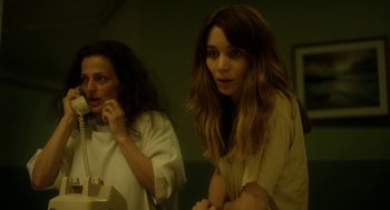 Movie still from “Side Effects” (2013), directed by Steven Soderbergh – Two women are standing in a dimly - lit room; Close Up shot, Over the shoulder angle