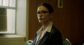 Movie still from “Side Effects” (2013), directed by Steven Soderbergh – A woman wearing glasses and a suit and tie; Close Up shot, Low angle