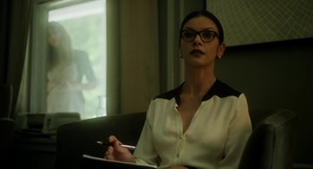 Movie still from “Side Effects” (2013), directed by Steven Soderbergh – A woman sitting in a chair holding a pen and a paper; Medium shot, Over the shoulder angle