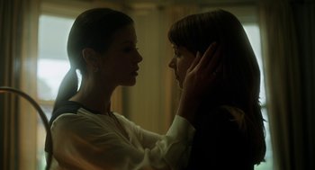 Two women touching each other's hair in a room