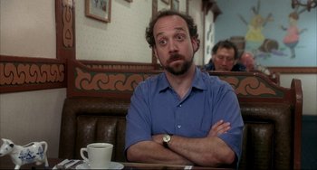Movie still from “Sideways” (2004), directed by Alexander Payne – A man sitting at a table with his arms crossed; Close Up shot, Over the shoulder angle