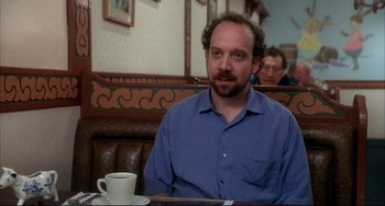 Movie still from “Sideways” (2004), directed by Alexander Payne – A man sitting at a table with a cup in front of him; Medium shot, Over the shoulder angle