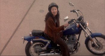Movie still from “Sideways” (2004), directed by Alexander Payne – A woman sitting on the back of a blue motorcycle; Wide shot, High angle