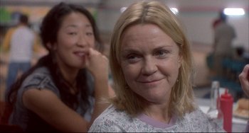 Movie still from “Sideways” (2004), directed by Alexander Payne – A woman smiles while another woman sits in the background; Close Up shot, Over the shoulder angle