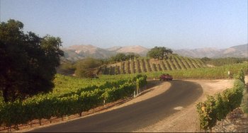 Movie still from “Sideways” (2004), directed by Alexander Payne – A car driving down a road near a bunch of hills; Extreme Wide shot, High angle