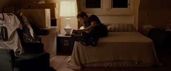Movie still from “Silver Linings Playbook” (2012), directed by David O. Russell – A man sitting on top of a bed reading a book; Wide shot, High angle