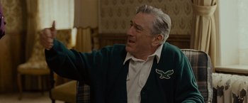 Movie still from “Silver Linings Playbook” (2012), directed by David O. Russell – An older man wearing a green cardigan and white shirt; Medium shot, Over the shoulder angle