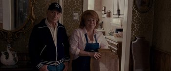 Movie still from “Silver Linings Playbook” (2012), directed by David O. Russell – An older man standing next to an older woman in a kitchen; Medium shot, Over the shoulder angle