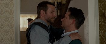 Movie still from “Silver Linings Playbook” (2012), directed by David O. Russell – Two men embracing each other in front of a staircase; Medium shot, Over the shoulder angle