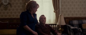 Movie still from “Silver Linings Playbook” (2012), directed by David O. Russell – An older man sitting next to a younger woman; Medium shot, Over the shoulder angle