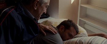 Movie still from “Silver Linings Playbook” (2012), directed by David O. Russell – An older man and a younger man laying on a bed; Medium shot, Over the shoulder angle