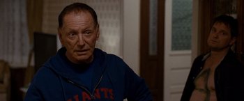 Movie still from “Silver Linings Playbook” (2012), directed by David O. Russell – An older man wearing a giants shirt and looking at the camera; Close Up shot, Over the shoulder angle