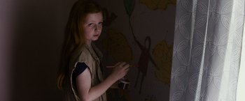 Movie still from “Sinister” (2012), directed by Scott Derrickson – A young girl is painting a mural on a wall; Medium shot, Over the shoulder angle