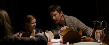 Movie still from “Sinister” (2012), directed by Scott Derrickson – A man sitting at a dinner table with a girl; Medium shot, Over the shoulder angle