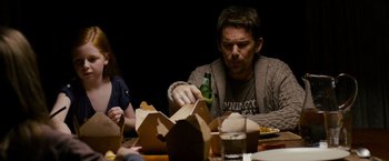 Movie still from “Sinister” (2012), directed by Scott Derrickson – A man sitting at a table with a bottle of beer; Medium shot, Over the shoulder angle