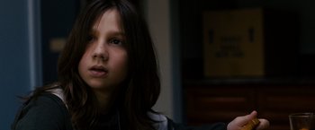 Movie still from “Sinister” (2012), directed by Scott Derrickson – A young girl with long dark hair wearing headphones looking at the camera; Close Up shot, Low angle