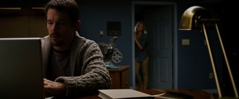 Movie still from “Sinister” (2012), directed by Scott Derrickson – A man sitting at a table in front of a woman; Medium shot, Over the shoulder angle