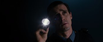 Movie still from “Sinister” (2012), directed by Scott Derrickson – A man is holding a flashlight in his hand; Close Up shot, Low angle