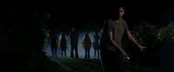 Movie still from “Sinister” (2012), directed by Scott Derrickson – A group of people standing in a field at night; Wide shot, Low angle