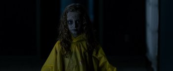 Movie still from “Sinister” (2012), directed by Scott Derrickson – A young girl in a yellow raincoat with makeup on her face; Close Up shot, Over the shoulder angle