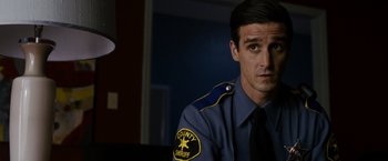 Movie still from “Sinister” (2012), directed by Scott Derrickson – A man in a police uniform sitting in front of a computer screen; Close Up shot, Over the shoulder angle