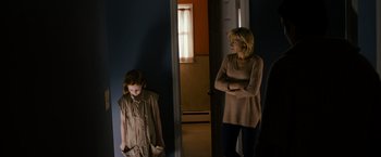 Movie still from “Sinister” (2012), directed by Scott Derrickson – A woman and a girl standing in front of a door; Medium shot, Over the shoulder angle