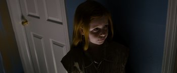 Movie still from “Sinister” (2012), directed by Scott Derrickson – A young girl with long red hair is looking at the camera; Close Up shot, High angle