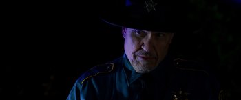 Movie still from “Sinister” (2012), directed by Scott Derrickson – A man in a police uniform with a hat on; Close Up shot, Low angle