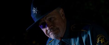 Movie still from “Sinister” (2012), directed by Scott Derrickson – A man in a police officer's uniform with a hat on; Close Up shot, Low angle