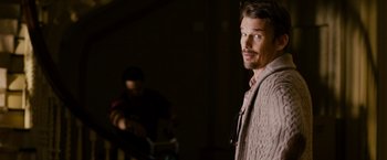 Movie still from “Sinister” (2012), directed by Scott Derrickson – A man standing next to another man in a room; Medium shot, Over the shoulder angle