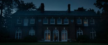 Movie still from “Sinister” (2012), directed by Scott Derrickson – A person standing in front of a building at night; Extreme Wide shot, Low angle