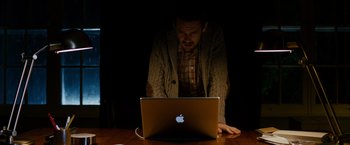 Movie still from “Sinister” (2012), directed by Scott Derrickson – A man sitting in front of an open laptop computer; Medium shot, High angle