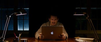 Movie still from “Sinister” (2012), directed by Scott Derrickson – A man sitting in front of an open laptop computer; Medium shot, High angle