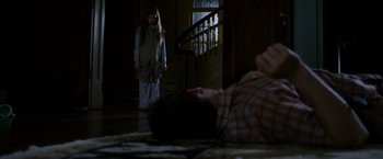 Movie still from “Sinister” (2012), directed by Scott Derrickson – A man laying on the ground next to a woman; Wide shot, High angle