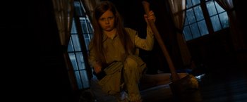 Movie still from “Sinister” (2012), directed by Scott Derrickson – A young girl is holding a wooden stick; Medium shot, High angle