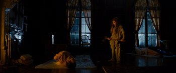 Movie still from “Sinister” (2012), directed by Scott Derrickson – A woman standing next to a man laying on the ground; Wide shot, Low angle