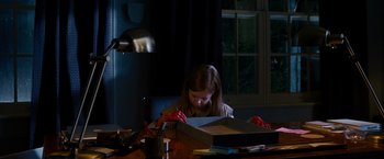 Movie still from “Sinister” (2012), directed by Scott Derrickson – A young girl sitting at a table with a box; Medium shot, High angle