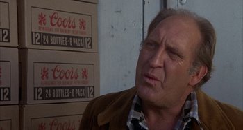 Movie still from “Smokey and the Bandit” (1977), directed by Hal Needham – An older man in a plaid shirt and a brown jacket; Close Up shot, Over the shoulder angle