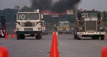 Movie still from “Smokey and the Bandit” (1977), directed by Hal Needham – A group of semi trucks driving down a street; Wide shot, High angle