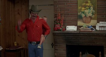 Movie still from “Smokey and the Bandit” (1977), directed by Hal Needham – A man in a cowboy hat holding a child in his arms; Medium shot, Over the shoulder angle