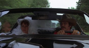 Movie still from “Smokey and the Bandit” (1977), directed by Hal Needham – A man and a woman in the back seat of a car; Wide shot, Over the shoulder angle