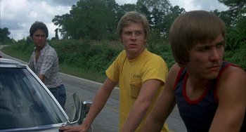 Movie still from “Smokey and the Bandit” (1977), directed by Hal Needham – A man in a yellow shirt is standing next to a motorcycle; Medium shot, Low angle