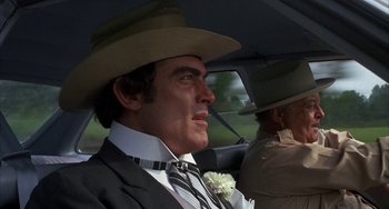 Movie still from “Smokey and the Bandit” (1977), directed by Hal Needham – A man in a suit and hat in the back of a car; Close Up shot, Over the shoulder angle