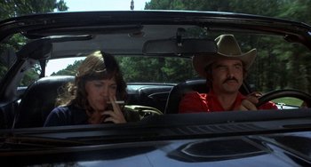 Movie still from “Smokey and the Bandit” (1977), directed by Hal Needham – A man and a woman sitting in the back seat of a car; Medium shot, High angle