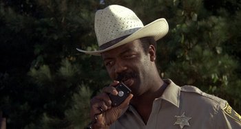 Movie still from “Smokey and the Bandit” (1977), directed by Hal Needham – A man in a cowboy hat is holding a cell phone; Close Up shot, Low angle