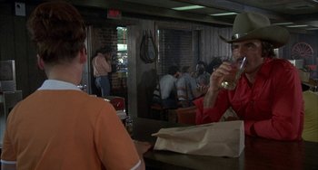 Movie still from “Smokey and the Bandit” (1977), directed by Hal Needham – Two people sitting at a table drinking wine; Medium shot, Over the shoulder angle