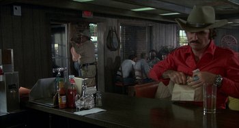 Movie still from “Smokey and the Bandit” (1977), directed by Hal Needham – A group of people sitting at a table in a restaurant; Medium shot, Over the shoulder angle
