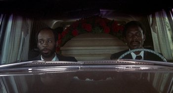 Movie still from “Smokey and the Bandit” (1977), directed by Hal Needham – Two men in suits in the back of a hearse; Medium shot, High angle